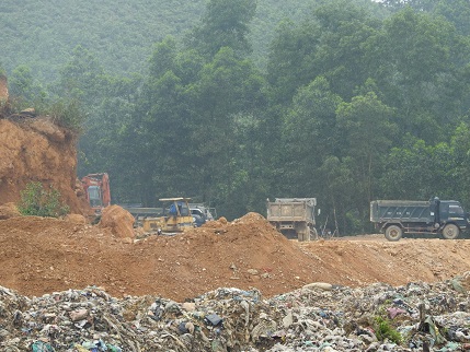 Hai chiếc máy xúc hoạt động liên tục khai thác đất bên bãi rác.
